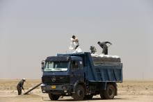 A farmer loads wheat grains onto a truck near the town of Makhmur