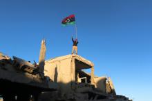 A fighter of Libyan forces allied with the U.N.-backed government waving a Libyan flag flashes victory sign as he stands atop the ruins of a house after forces finished clearing Ghiza Bahriya, the final district of the former Islamic State stronghold of Sirte, Libya. PHOTO BY REUTERS/Hani Amara