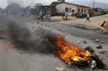 Residents move past a burning barricade on a rock strewn street in Bujumbura's Niyakabiga district on Presidential election day in Burundi, July 21, 2015. PHOTO BY REUTERS/Mike Hutchings