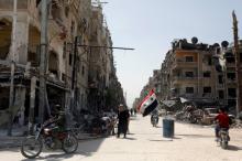 A Syrian flag flutters along a damaged street at the city of Douma in Damascus, Syria, April 20, 2018. PHOTO BY REUTERS/Omar Sanadiki