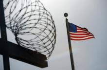 A U.S. flag flies above a razorwire-topped fence at a detention facility, December 10, 2008. PHOTO BY REUTERS/Mandel Ngan