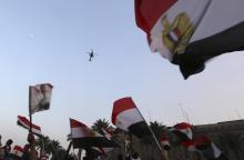 Egyptians wave national flags as a military helicopter circles over Tahrir Square, after the swearing-in ceremony of President Abdel Fattah al-Sissi, in Cairo, June 8, 2014. PHOTO BY REUTERS/Mohamed Abd El Ghany