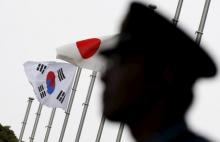 A police officer stands guard near Japan and South Korea national flags at a hotel, in Tokyo, June 22, 2015. PHOTO BY REUTERS/Toru Hanai