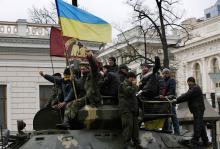 Anti-Yanukovich protesters wave a Ukranian flag atop a Ukranian Army Armoured Personnel Carrier (APC) outside the parliament building in Kiev