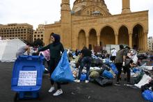A young woman sorts recycling into a bin in front of the Mohammad al-Amin mosque in Beirut, October 23, 2019. PHOTO BY Thomson Reuters Foundation/Finbar Anderson