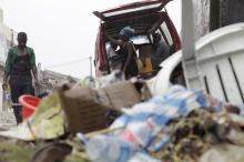 People walk past a pile of garbage along a street during rainfall, in Luanda, Angola, February 10, 2016. PHOTO BY REUTERS/Herculano Corarado