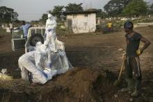 A grave digger waits as health workers unload the bodies of Ebola victims for burial at a cemetery in Freetown, December 17, 2014. PHOTO BY REUTERS/Baz Ratner