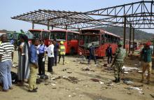 A military officer stands guard near damaged vehicles at the scene of a bomb explosion at Nyanyan, in Abuja