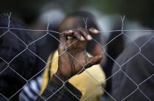 A stranded African migrant holds onto a police fence during a protest at the Greek-Macedonian border near the Greek village of Idomeni, November 26, 2015. PHOTO BY REUTERS/Yannis Behrakis