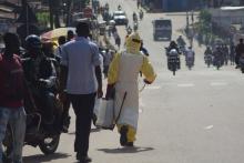 A health worker with disinfectant spray walks down a street outside the government hospital in Kenema