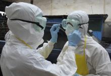 Health workers wearing protective clothing prepare themselves before to carrying an abandoned dead body presenting with Ebola symptoms at Duwala market in Monrovia