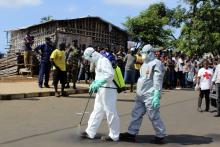 Health workers spray themselves with chlorine disinfectants after removing the body a woman who died of Ebola virus in the Aberdeen district of Freetown, Sierra Leone