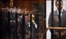 Egypt's former president Hosni Mubarak waves to his supporters with his sons Gamal (L) and Alaa (R) inside a cage in a courtroom during them trial at the police academy, on the outskirts of Cairo, May 9, 2015. PHOTO BY REUTERS/Amr Abdallah Dalsh