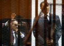 Egypt's former president Hosni Mubarak (L) waves to his supporters with his sons Alaa (R) and Gamal (unseen) inside a cage in a courtroom during their trial at the police academy, on the outskirts of Cairo, May 9, 2015. PHOTO BY REUTERS/Amr Abdallah Dalsh