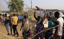 Displaced people walk past razor wire at Tomping camp, where some 15,000 displaced people who fled their homes are sheltered by the United Nations, near Juba