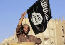 A militant Islamist fighter waving a flag, cheers as he takes part in a military parade along the streets of Syria's northern Raqqa province, June 30, 2014. PHOTO BY REUTERS/Stringer