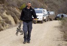 An Israeli police explosive expert carries the remains of a rocket after it landed near the northern town of Kiryat Shmona