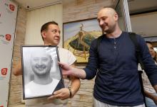 Russian dissident journalist Arkady Babchenko (R) takes his portrait from deputy chief of the Crimean Tatar channel ATR Aider Muzhdabaiev as he visits the office of the channel in Kiev, Ukraine, May 31, 2018. PHOTO BY REUTERS/Valentyn Ogirenko