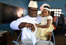 Julius Maada Bio, the presidential candidate for the Sierra Leone People's Party (SLPP), carries his daughter as he casts his vote during Sierra Leone's general election in Freetown, Sierra Leone, March 7, 2018. PHOTO BY REUTERS/Olivia Acland