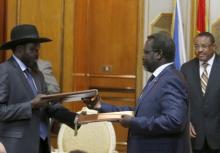 Ethiopian Prime Minister Hailemariam Desalegn (R) looks on as South Sudan's rebel leader Riek Machar (C) and South Sudan's President Salva Kiir (L) exchange signed peace agreement documents in Addis Ababa, May 9, 2014. PHOTO BY REUTERS/Goran Tomasevic