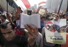 A supporter of the Muslim Brotherhood and ousted Egyptian President Mohamed Mursi holds a copy of the Koran as others shout slogans against the military and the interior ministry during a protest in the Cairo suburb of Matariya, November 28, 2014. PHOTO BY REUTERS/Mohamed Abd El Ghany