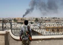 A Kurdish fighter from the People's Protection Units (YPG) looks at a smoke after an coalition airstrike in Raqqa, Syria, June 16, 2017. PHOTO BY REUTERS/Goran Tomasevic