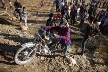 A Syrian Kurd pushes his motorcycle as he crosses into Turkey on the Turkish-Syrian border, near the southeastern town of Suruc in Sanliurfa province