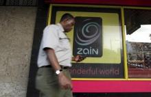 A man uses his mobile phone as he walks past a Zain customer care shop in Nairobi, February 15, 2010. PHOTO BY REUTERS/Thomas Mukoya
