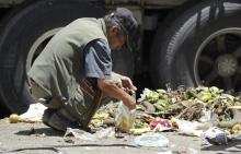 A man looks for leftover vegetables and fruits at a local market in Bogota