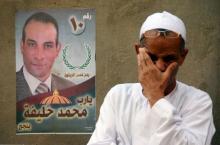 A man is seen near an election poster for parliamentary candidate Mohamed Khalifa at a village in Minya governorate, south of Cairo, Egypt, October 8, 2015. PHOTO BY REUTERS/Stringer