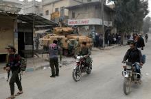Men ride motorcycles as Turkish soldiers are seen with their military vehicle in the center of Afrin, Syria, March 24, 2018. PHOTO BY REUTERS/Khalil Ashawi