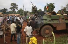 Men stand facing French soldiers as they block a road which French army vehicles were travelling on, during a protest in Bambari