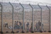 African would-be immigrants stand near the border fence between Israel and Egypt near the Israeli village of Be'er Milcha in a file photo. PHOTO BY REUTERS/ Nir Elias