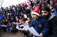 Migrants sing the traditional German christmas carol "Oh christams tree" during a Christmas gathering, organized by local relief organization "Die Johanniter", with christmas presents for the children at the refugee camp in Hanau, Germany, December 24, 2015. PHOTO BY REUTERS/Kai Pfaffenbach
