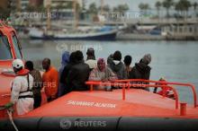 Migrants, who are part of a group intercepted aboard a dinghy off the coast in the Mediterranean sea, stand on a rescue boat, October 22, 2016. PHOTO BY REUTERS/Jon Nazca