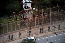 African migrants sit on top of a border fence during an attempt to cross into Spanish territories, between Morocco and Spain's north African enclave of Ceuta, December 9, 2016. PHOTO BY REUTERS/M. Martin