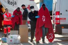 Migrants, who are part of a group intercepted aboard a dinghy off the coast in the Mediterranean sea, are assisted by a member of Spanish Red Cross and a police officer after arriving on a rescue boat at a port in Malaga, southern Spain, January 1, 2017. PHOTO BY REUTERS/Jon Nazca