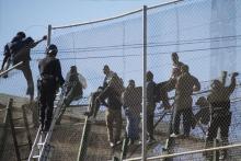 African migrants sit on top of a border fence during an attempt to cross into Spanish territories, between Morocco and Spain's north African enclave of Melilla, November 21, 2015. PHOTO BY REUTERS/Jesus Blasco de Avellaneda