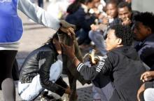 Dejen Asefaw (R), a 24-year-old Eritrean, receives a pullover from a volunteer at the Bolzano railway station, northern Italy, May 28, 2015. PHOTO BY REUTERS/Stefano Rellandini