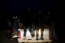 Light from vehicle illuminates the legs of migrants siting at the back of a truck as it is driven through a dusty road at night from the desert town of Agadez, Niger, May 25, 2015. PHOTO BY REUTERS/Akintunde Akinleye