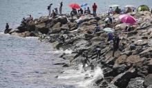 Migrants are seen on the rocks of the seawall at the Saint Ludovic border on the Mediterranean Sea between Vintimille, Italy and Menton, France, June 17, 2015. PHOTO BY REUTERS/Eric Gaillard