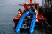Migrants intercepted aboard a dinghy off the coast in the Mediterranean Sea, help rescuers to unload their dinghy from a rescue boat after arriving at the port of Malaga, southern Spain, July 7, 2018. PHOTO BY REUTERS/Jon Nazca