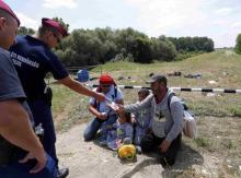 Hungarian police give water to migrants from Syria who crossed the border from Serbia to Hungary, walking on the dam near the Tisza river near the city of Szeged, Hungary, June 29, 2015. PHOTO BY REUTERS/Laszlo Balogh