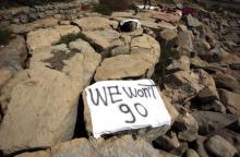 A migrant rests near a banner that reads "We won't go" on the rocks of the seawall at the Saint Ludovic border crossing on the Mediterranean Sea between Vintimille, Italy and Menton, France, June 16, 2015. PHOTO BY REUTERS/Eric Gaillard