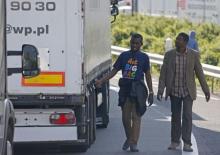 Migrants check the trailer of a truck during an attempt to make a clandestine crossing to England through the Channel tunnel as lorries wait on a road which leads to the Channel Tunnel terminal in Coquelles near Calais, northern France, July 1, 2015. PHOTO BY REUTERS/Vincent Kessler