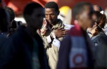 A member of police takes a picture of a migrant after disembarking from tug boat Asso29 in the Sicilian harbour of Pozzallo, southern Italy, May 4, 2015. PHOTO BY REUTERS/Antonio Parrinello