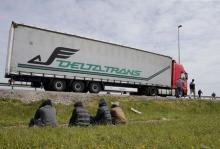 Migrants sit on an embankment near a truck on the road that leads to the Channel tunnel in the hopes of boarding a lorry to make a clandestine crossing to England, in Calais, France, May 22, 2015. PHOTO BY REUTERS/Pascal Rossignol