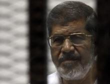 Ousted Egyptian president Mohamed Mursi stands behind bars during his trial at a court in Cairo