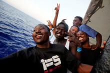 Mohamed (L), 21, from Sudan, takes a selfie with friends onboard NGO Proactiva Open Arms rescue boat in central Mediterranean Sea, August 3, 2018. PHOTO BY REUTERS/Juan Medina