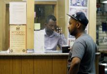 Mohammed Ahamed (R) waits as Shakir Hussein, owner of money transfer business Mustaqbal Express in Minneapolis, wires money to his ex-wife in Somalia